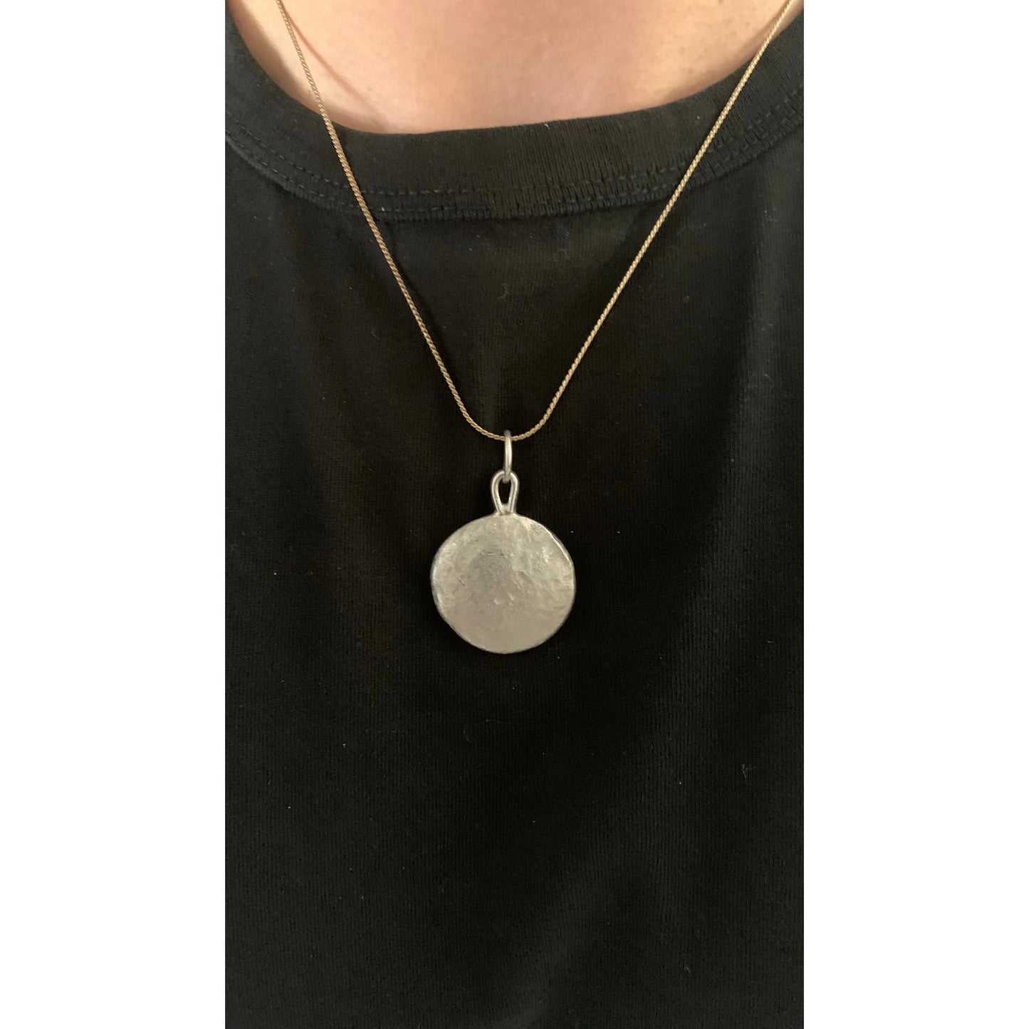 Backside image of a one ounce silver pendant being worn