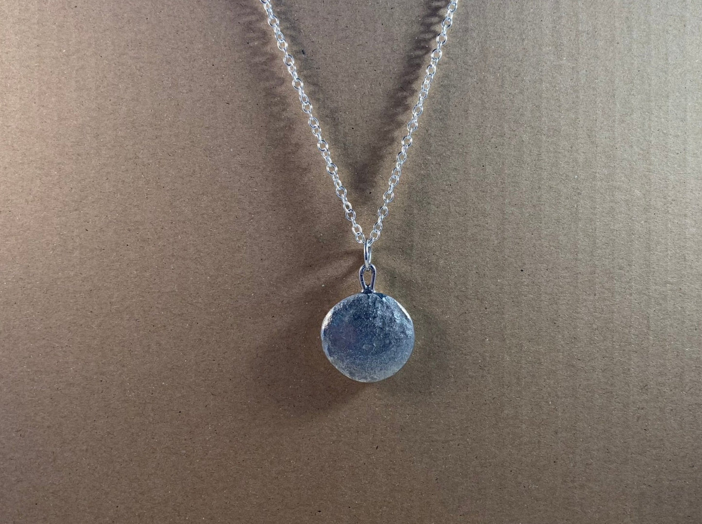 Backside image of a one ounce silver pendant on a chain