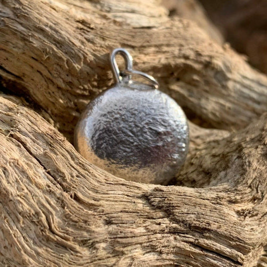 One ounce silver pendant on a log 