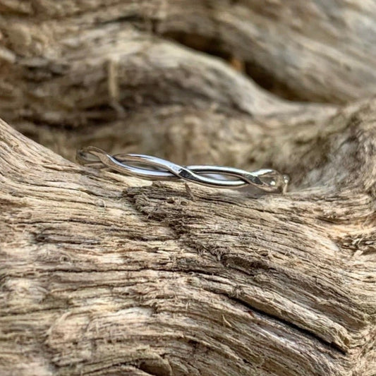 Twisted silver ring on a log