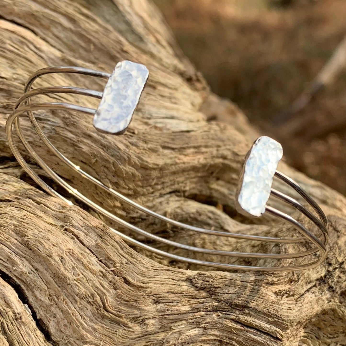 A silver bracelet on a log 