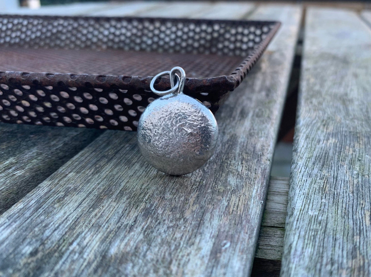 Frontside image of a one ounce silver pendant against a metal tray