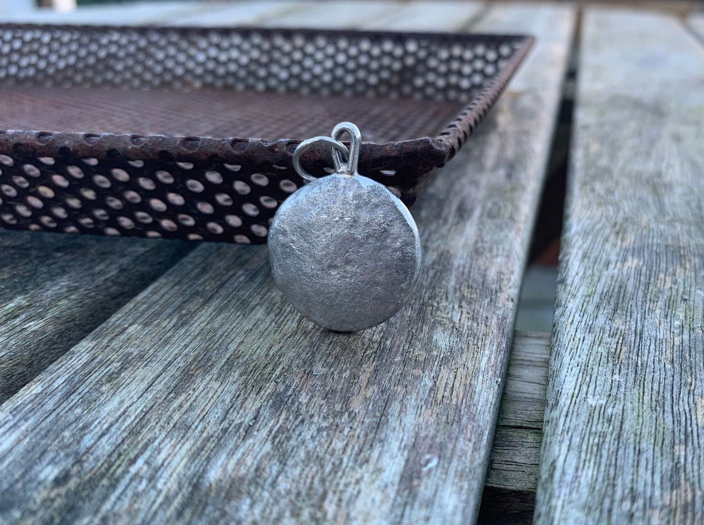 Backside image of a one ounce silver pendant against a metal tray