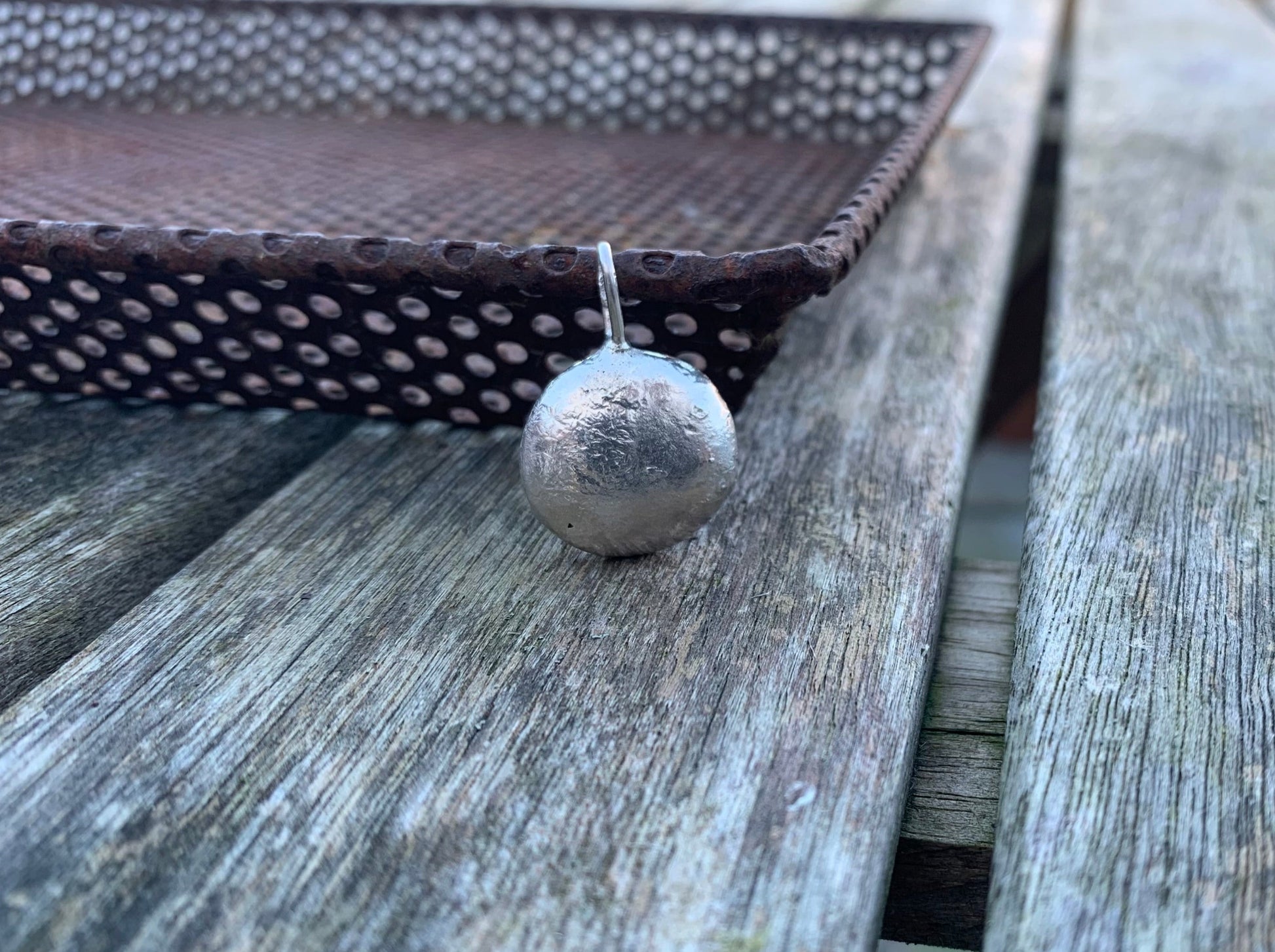 Front side image of half ounce pendant against a metal tray