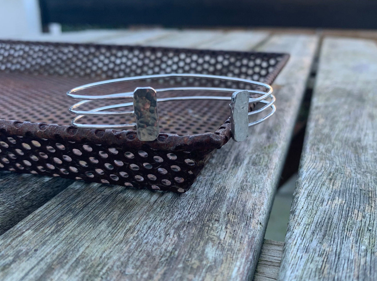 A silver bracelet on a metal tray